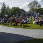 People on chairs watching an outdoors performance