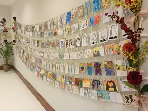 over 800 postcards on display on a wall, created by school children