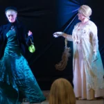 Two actresses in costume perform a play about two historical female figures.