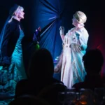 Two actresses in costume perform a play about two historical female figures.